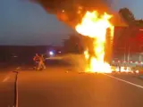 Momento en el que los bomberos intentan apagar el camión incendiado.