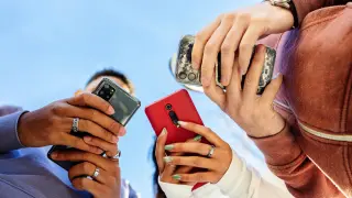 Tres jóvenes utilizando el teléfono móvil.