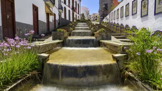 A pesar de que se la conoce como el Balcón del Atlántico por sus increíbles vistas, Firgas carece de salida al mar. En su casco histórico, la pendiente natural del Paseo de Gran Canaria permitió la construcción, en piedra de cantería, de esta fuente en cascada que se prolonga durante treinta metros. En uno de sus laterales, bancos y escudos decorados con azulejos andaluces nos recuerdan cuáles son los 21 municipios de la isla.