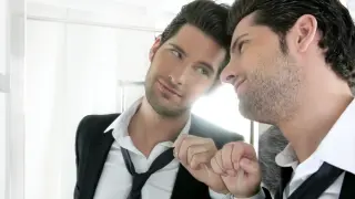 Joven narcisista guapo mirándose en un espejo.