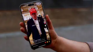 Una persona posando con su móvil muestra la página de TikTok @realdonaldtrump.