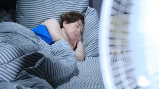 Mujer durmiendo con un ventilador al lado