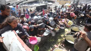 Decenas de personas reciben alimentos en un punto de caridad en la ciudad de Gaza.