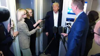 El presidente Donald Trump habla con los periodistas a bordo del Air Force One durante una parada para repostar en la base aérea de Mildenhall, cerca de Bury St. Edmunds, en el este de Inglaterra, en la madrugada del martes 14 de octubre de 2025, mientras regresa a Washington.