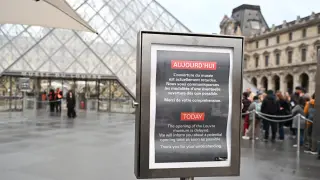 A board reads that the opening of the Louvre museum is delayed, but it remains closed for the day after Sunday's jewels robbery, Monday, Oct. 20, 2025 in Paris. (AP Photo/Emma Da Silva)