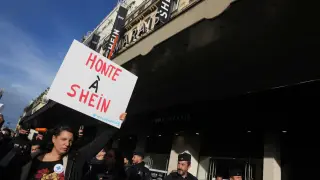 A demonstrator holds a poster reading "Shame on Shein" outside the BHV department store where fast fashion powerhouse Shein's first permanent store is set to open, Wednesday, Nov. 5, 2025 in Paris. (AP Photo/Thibault Camus)