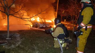 Los bomberos apagan un coche en llamas tras un ataque ruso en un área residencial, en Járkov (Ucrania).