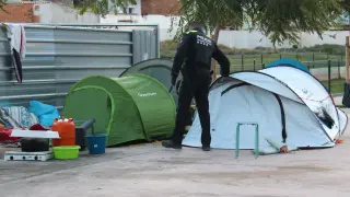 Un agente de la Guardia Urbana de Badalona inspecciona tienda por tienda para despertar a las personas que han dormido esta pasada noche en la plaza del Cotonificio de Badalona.