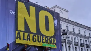 Greenpeace activists hang a banner reading in Spanish, "Not to war" in downtown Madrid, Spain, Tuesday, March 10, 2026. (AP Photo/Bernat Armangue)