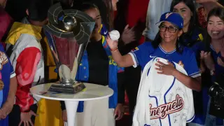 Venezuela's acting President Delcy Rodriguez holds an autographed ball next to the World Baseball Classic trophy a day after her team's victory over the United States in the championship match in Caracas, Venezuela, Wednesday, March 18, 2026. (AP Photo/Ariana Cubillos)