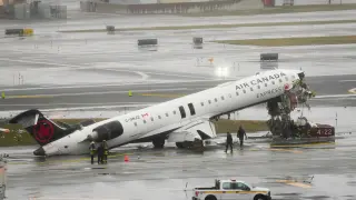 Firefighters and investigators examine the site, Monday, March 23, 2026, where an Air Canada jet came to rest after colliding with a Port Authority firetruck at LaGuardia Airport, after landing Sunday night in New York. (AP Photo/Seth Wenig)