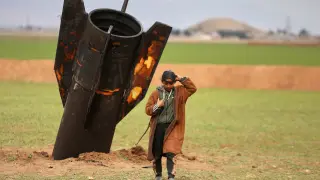 Un pastorcillo se aleja de un proyectil iraní sin explotar que cayó en un campo abierto en las afueras de Qamishli, en el este de Siria.