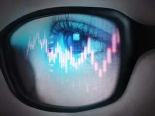 The reflection of the stock graph on a young adult women's glasses.