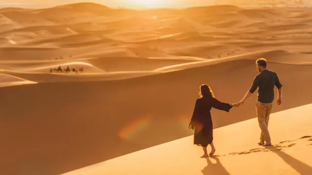 Pareja caminando por el desierto del Sahara al atardecer.