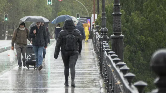 Peatones caminan bajo la lluvia en Sevilla, este domingo.