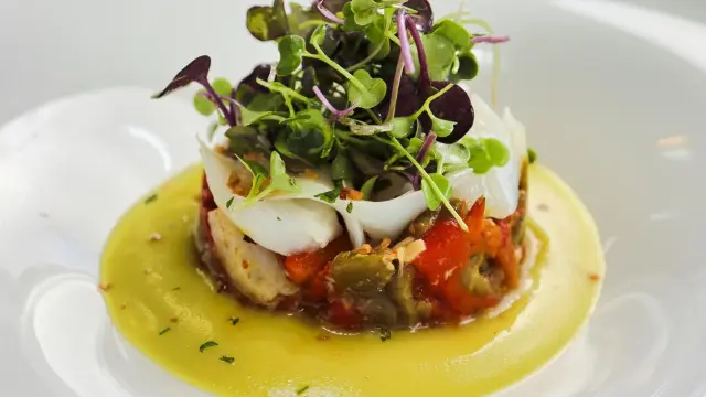 Timbal de bacalao con micro mezclum mix sakura, pimientos asados y pil pil.
