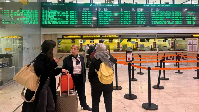 Dos usuarias, cargadas con maletas y mochilas, se acercan a las taquillas para solicitar información.