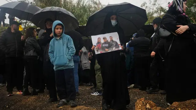 Una mujer sostiene un cartel que muestra a los periodistas Ali Shaib y Fatima Fatouni, y al camarógrafo Ali Fatouni, asesinados por Israel en Líbano, durante su funeral.