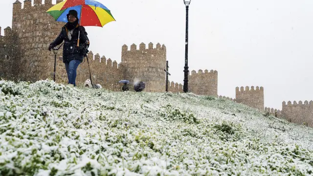 Una persona pasea junto a la muralla de Ávila este viernes, cubierta de una fina capa de nieve.