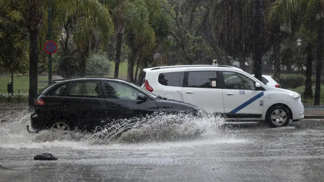 Varios coches circulan bajo la lluvia que ha caído en Málaga este sábado.