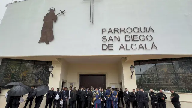 Costaleros, nazarenos y músicos se resguardan de la lluvia en la Iglesia de donde debería salir la Hermandad de El Sol en Sevilla, este sábado.