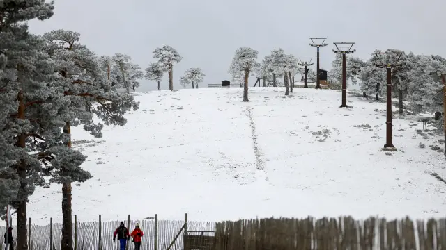 Dos personas pasean cerca de la estación de esquí de Puerto de Navacerrada, en Madrid, esta Semana Santa.