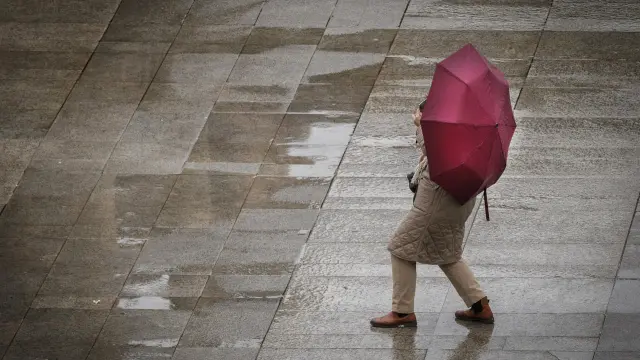 Una persona toma una fotografía bajo la intensa lluvia caída este viernes en Pamplona.