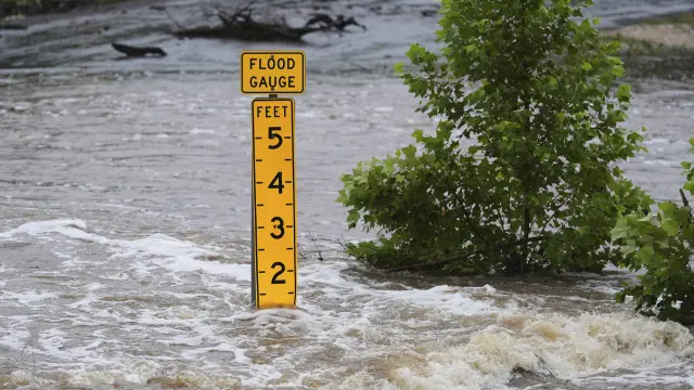 A flood gauge marks the height of water flowing over a farm-to-market road near Kerrville, Texas, on Friday, July 4, 2025. (AP Photo/Eric Gay)
