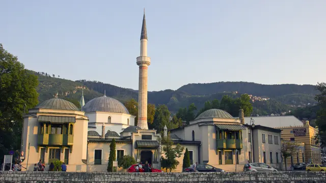 Sarajevo, Bosnia and Herzegovina - August 31, 2015: People on the way near the Miljacka river and the Old Town, with minaret and riverside boulvard in Sarajevo. Sarajevo is the capital city of Bosnia and Herzegovina.