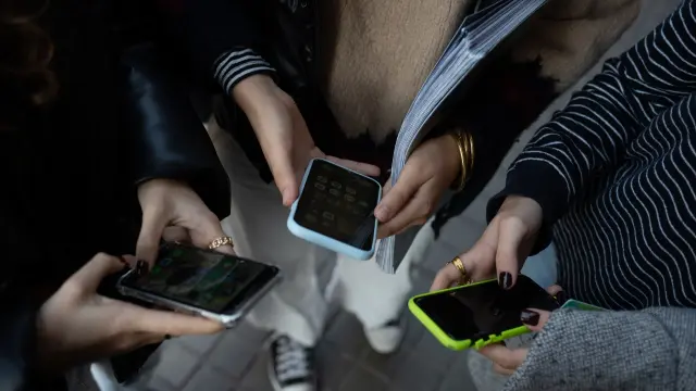 Varias personas usan el teléfono móvil en Barcelona.