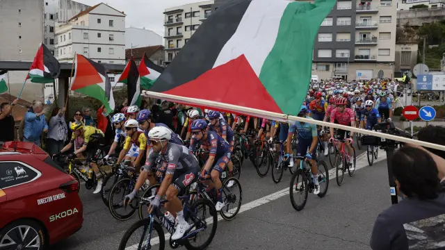 Los manifestantes ondean banderas de Palestina en la salida de la decimosexta etapa.