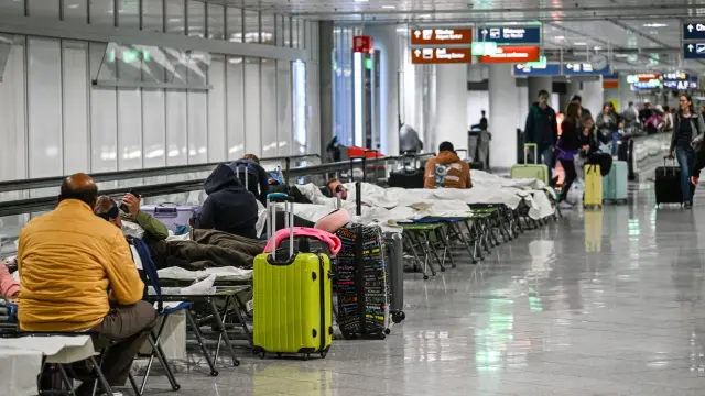 People wait on cots after drone sightings and flight cancellations at  at Munich Airport, Friday, Oct.3, 2025. (Jason Tschepljakow/dpa via AP)