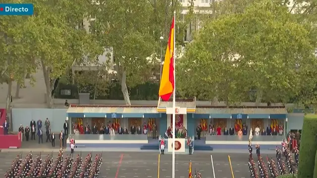 Izado de la bandera de España con la tribuna real al fondo.