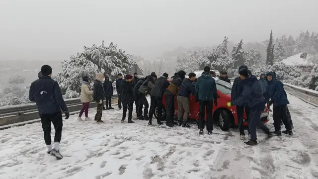 ALPEDRETE (MADRID), 28/01/2026.- Varias personas tratan de mover un vehículo atravesado en la carretera M-519 a la altura de Galapagar, este miércoles, en el que la borrasca Kristin deja nieve en la región de Madrid. El temporal de frío, lluvia y nieve que atraviesa estos días la península mantiene afectados todos los puertos en la Comunidad Madrid por la nieve. Es necesario el uso de cadenas o neumáticos de invierno en todos los puertos de la Comunidad y en desde el kilómetro 13 de la A-6. EFE/Álvaro Blanco
