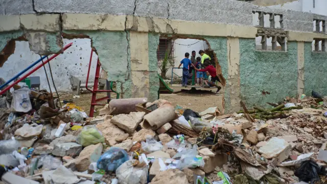 Foto de uno niños montados en un tiovivo rodeado de basura en la Habana.
