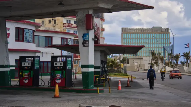 Foto de un hombre pasando junto a un gasolinera que se ha quedado sin combustible.