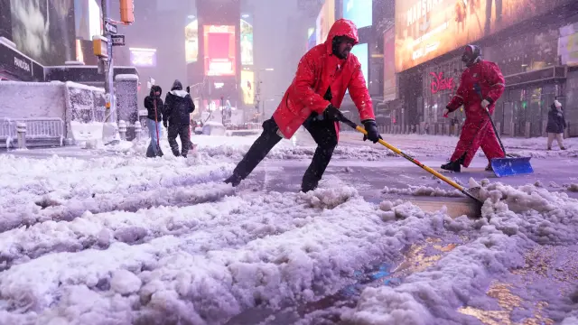 A worker with the Times Square Alliance sanitation crew shovels snow in Times Square, Monday, Feb. 23, 2026, in New York. (AP Photo/Seth Wenig)