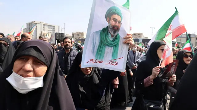 Tehran (Iran (Islamic Republic Of)), 18/03/2026.- An Iranian mourner holds a poster of Iranian Supreme Leader Ayatollah Mojtaba Khamenei as they take part in a funeral procession in Tehran, Iran, 18 March 2026. Thousands gathered in Enghelab Square to honor Ali Larijani, Secretary of the Supreme National Security Council, and Major General Gholamreza Soleimani, head of the Basij paramilitary forces; both were killed in airstrikes on 17 March. The funeral also served as a memorial for the dozens of Iranian sailors killed aboard the Iranian destroyer IRIS Dena, which was sunk by US forces in the Indian Ocean earlier this month. A joint US-Israeli military operation continues to target multiple locations across Iran since 28 February 2026. (Teherán) EFE/EPA/ABEDIN TAHERKENAREH