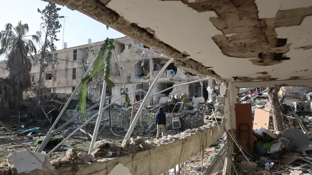 Varias personas observan la escena del impacto directo de un misil iraní en un barrio residencial de Dimona, Israel.