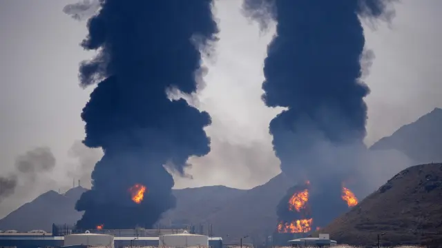 FILE - Plumes of smoke and fire rise after debris from an intercepted Iranian drone struck an oil facility, according to authorities, in Fujairah, United Arab Emirates, March 14, 2026. (AP Photo/Altaf Qadri, File)
