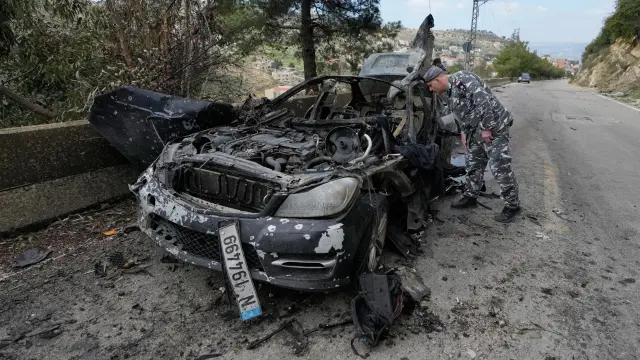 Un policía inspecciona el coche calcinado en el que viajaban tres periodistas libaneses asesinados en un ataque israelí este sábado, al sur del Líbano.