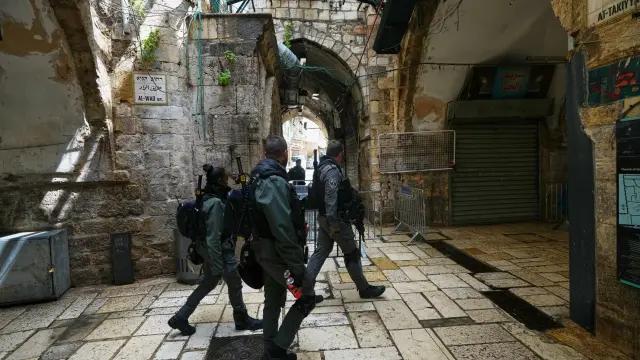 Agentes de la policía fronteriza israelí recorren una calle vacía, pasando junto a tiendas cerradas, en la Ciudad Vieja de Jerusalén, el pasado viernes 27 de marzo de 2026.