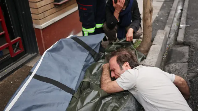 Un hombre llora mientras abraza el cuerpo de un ser querido estadounidense-israelí muerto tras un ataque en Teherán, Irán.