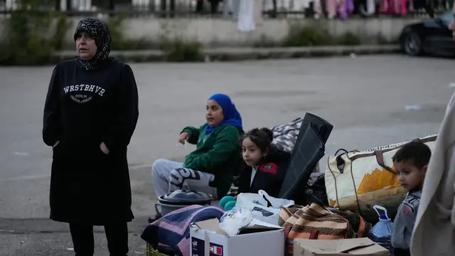A displaced family sits next to packed belongings as they wait for an official ceasefire decision between Iran and the United States that they hope will include Lebanon and allow them to return to their villages, in the southern port city of Sidon, Lebanon, Wednesday, April 8, 2026. (AP Photo/Mohammed Zaatari)