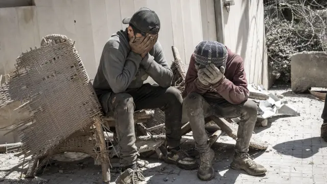 Dos niños se cubren la cara para protegerse del polvo por las tareas de desescombro en Beirut tras la masacre del miércoles.