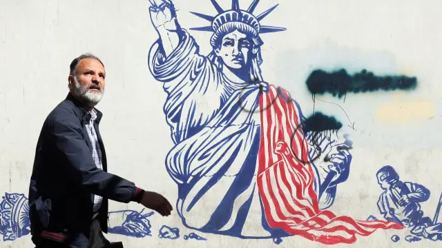 Un hombre iraní camina junto a un mural antiestadounidense cerca de la antigua embajada de Estados Unidos en Teherán, Irán.