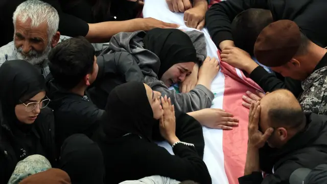 Varias personas lloran ante el ataúd de un miembro de las Fuerzas de Seguridad del Estado libanesas durante una procesión fúnebre por los trece cuerpos de miembros de dichas fuerzas en la ciudad costera de Sidón, al sur del Líbano.