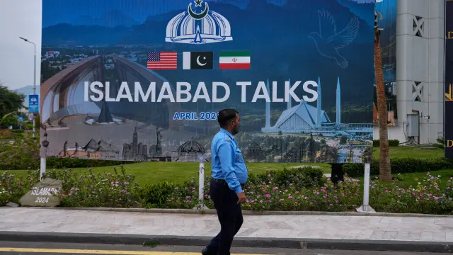 Un agente de policía pasa junto a una valla publicitaria sobre las negociaciones entre Estados Unidos e Irán en Islamabad, Pakistán.