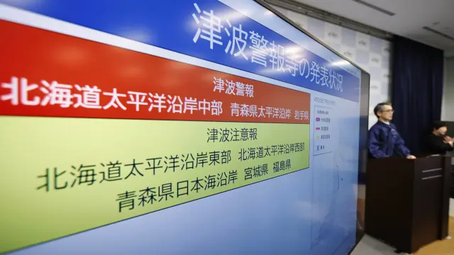 An official of the Japan Meteorological Agency speaks near a monitor showing a tsunami alert during a news conference at the agency in Tokyo, Monday, April 20, 2026, after an earthquake that struck off the northern Japanese coast. (Masanori Kumagai/Kyodo News via AP)