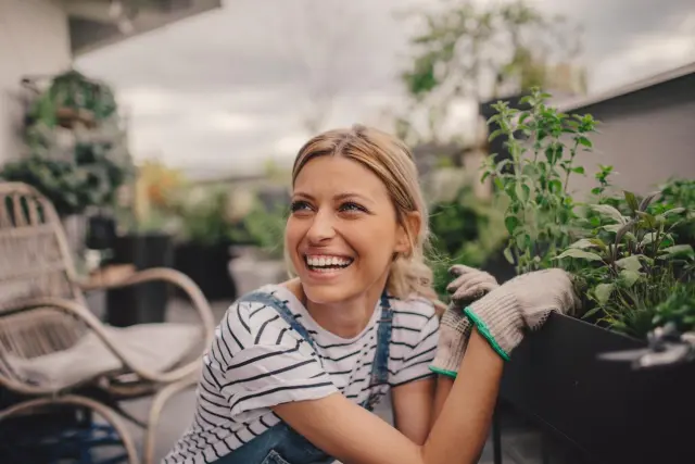 Mujer arreglando plantas jardín.